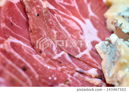 Close-up of thinly sliced cured ham and blue cheese on a gourmet platter 143467302