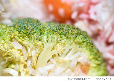 Macro close-up shot of fresh green broccoli floret mixed with white rice grains Macro close-up shot of fresh green broccoli floret mixed with white rice grains 143467383