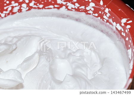 Close-up of freshly whipped white cream inside a bright red mixing bowl Close-up of freshly whipped white cream inside a bright red mixing bowl 143467499