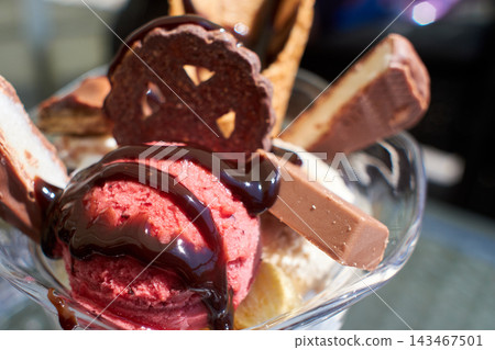 Close-up of a delicious raspberry ice cream sundae decorated with chocolate syrup and cookies Close-up of a delicious raspberry ice cream sundae decorated with chocolate syrup and cookies 143467501