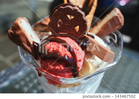 Delicious ice cream sundae decorated with chocolate sauce and cookies in a glass cup Delicious ice cream sundae decorated with chocolate sauce and cookies in a glass cup 143467502