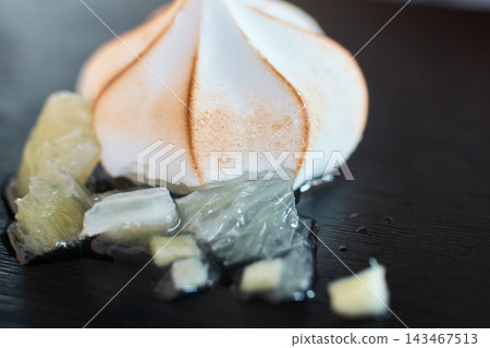 Close-up of a toasted meringue dessert served with citrus fruit pieces on a plate Close-up of a toasted meringue dessert served with citrus fruit pieces on a plate 143467513