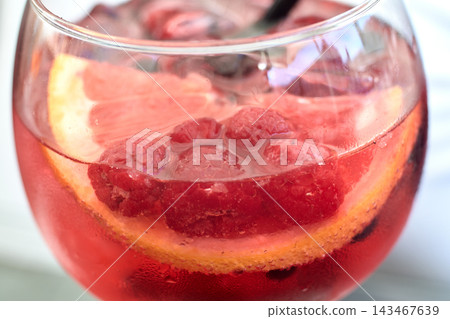 Close-up view of a refreshing pink gin cocktail with fresh raspberries and citrus slices Close-up view of a refreshing pink gin cocktail with fresh raspberries and citrus slices 143467639