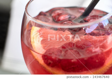 Close-up of a refreshing pink gin cocktail garnished with fresh raspberries and citrus slices Close-up of a refreshing pink gin cocktail garnished with fresh raspberries and citrus slices 143467640