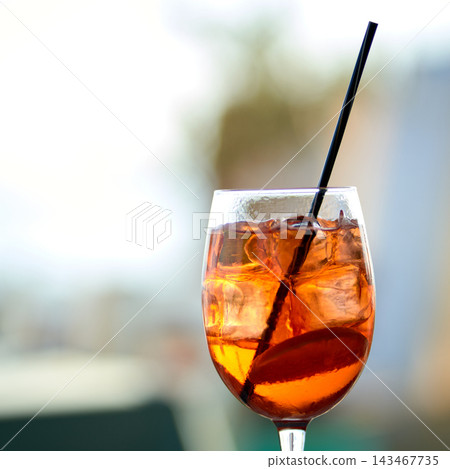 Close-up of a refreshing orange spritz cocktail with ice cubes and a black straw Close-up of a refreshing orange spritz cocktail with ice cubes and a black straw 143467735