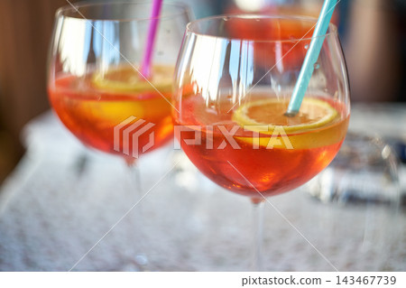 Close-up of two wine glasses filled with orange aperitif cocktail garnished with citrus slices 143467739
