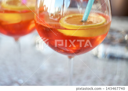 Close-up of refreshing orange spritz cocktails garnished with citrus slices and a straw Close-up of refreshing orange spritz cocktails garnished with citrus slices and a straw 143467740