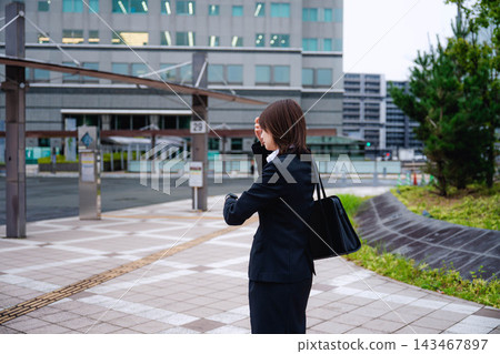 一位女商人正在街上看手錶。 一位女商人正在街上看手錶。 143467897