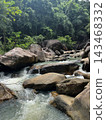 Mountain stream flowing over large rocks in tropical forest 143468332