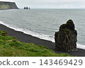 Arnardrangur rock stack on Reynisfjara black sand beach with Reynisdrangar stacks Iceland 143469429