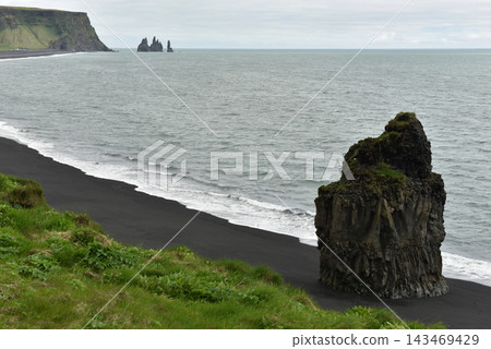 Arnardrangur rock stack on Reynisfjara black sand beach with Reynisdrangar stacks Iceland Arnardrangur rock stack on Reynisfjara black sand beach with Reynisdrangar stacks Iceland 143469429