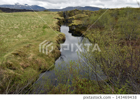 Glacial water filling a rocky volcanic fissure in a mossy rift valley, Iceland Glacial water filling a rocky volcanic fissure in a mossy rift valley, Iceland 143469438
