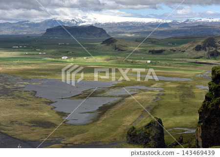 Distant glacier and vast green valley seen from Dyrholaey, Iceland Distant glacier and vast green valley seen from Dyrholaey, Iceland 143469439