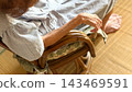 An elderly woman sitting on a wisteria chair (back view) 143469591