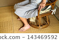 An elderly woman tries to stand up from a wisteria chair. 143469592