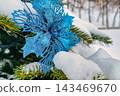 A tree is covered with snow and adorned with a blue ornament. The scene captures the essence of winter during the holiday season 143469670