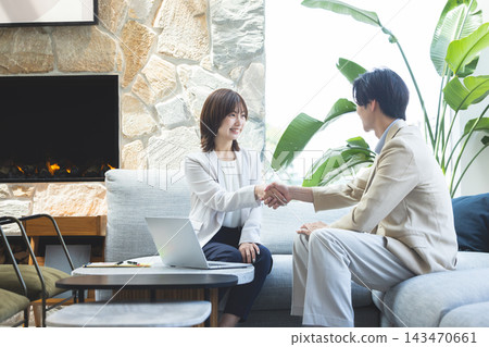 一男一女面帶微笑地握手。 143470661