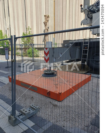 Construction Site Crane Outrigger On Orange Stabilizer Pad Behind Temporary Safety Fence Construction Site Crane Outrigger On Orange Stabilizer Pad Behind Temporary Safety Fence 143470894