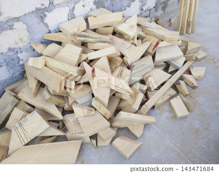 A pile of wooden offcuts of various shapes and sizes lying on a concrete floor. A pile of wooden offcuts of various shapes and sizes lying on a concrete floor. 143471684