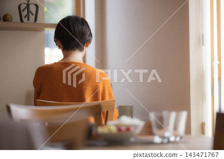 A Japanese woman's back view, showing her suffering from menopausal mood swings and seasonal affective disorder in autumn and winter, conveying feelings of loneliness and apathy, without a face. A Japanese woman's back view, showing her suffering from menopausal mood swings and seasonal affective disorder in autumn and winter, conveying feelings of loneliness and apathy, without a face. 143471767