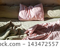 Unmade Bed with Soft Linen Bedding in Morning Sunlight. Cozy Home Atmosphere 143472557