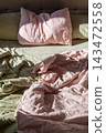 Unmade Bed with Soft Linen Bedding in Morning Sunlight for Home Comfort 143472558