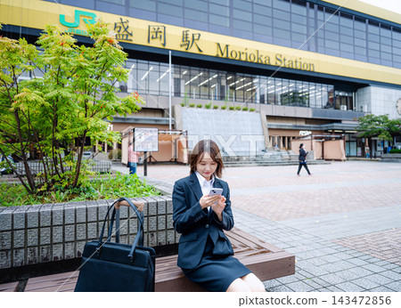 一位女商人坐在火車站的長椅上。 一位女商人坐在火車站的長椅上。 143472856