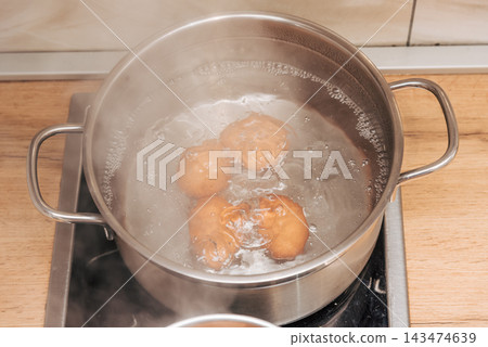 Brown chicken eggs boiled metal pots on stove kitchen, cooking healthy breakfast Brown chicken eggs boiled metal pots on stove kitchen, cooking healthy breakfast 143474639