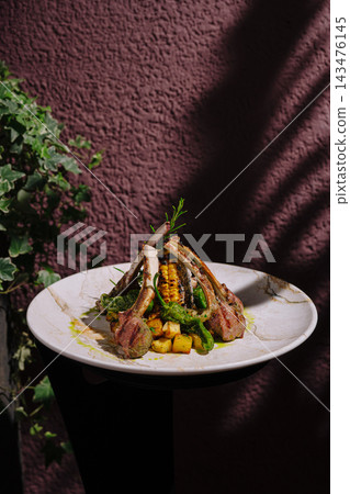 Grilled lamb chops with corn, potatoes, and rosemary on a plate 143476145