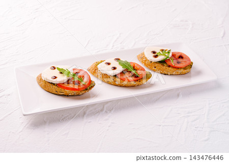 Caprese bruschetta appetizers with mozzarella, tomato, and balsamic glaze 143476446
