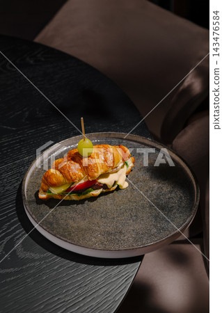 Croissant sandwich with burger patty and grape on plate 143476584