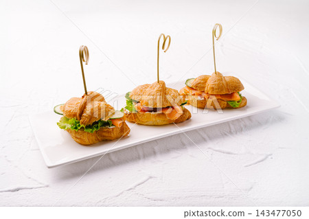 Croissant sandwiches with smoked salmon, cream cheese, lettuce, and cucumber Croissant sandwiches with smoked salmon, cream cheese, lettuce, and cucumber 143477050