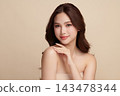 A beautiful young Asian woman with clean, fresh skin against a beige background. Skincare, facial treatment, cosmetology, beauty, and spa. An elegant portrait of an Asian woman. 143478344