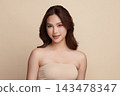 A beautiful young Asian woman with clean, fresh skin against a beige background. Skincare, facial treatment, cosmetology, beauty, and spa. An elegant portrait of an Asian woman. 143478347