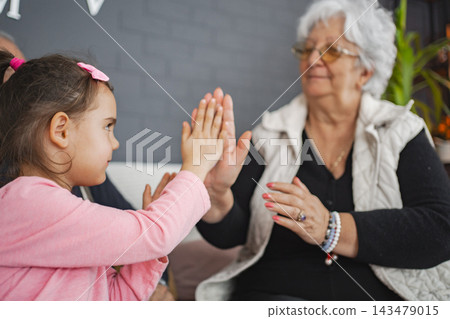 Joyful clapping game with grandma and granddaughter Joyful clapping game with grandma and granddaughter 143479015