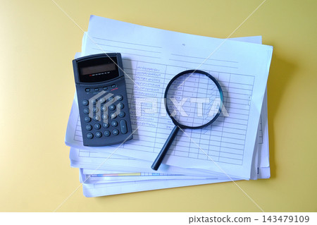 Magnifying glass and calculator on Stack of documents. Magnifying glass and calculator on Stack of documents. 143479109