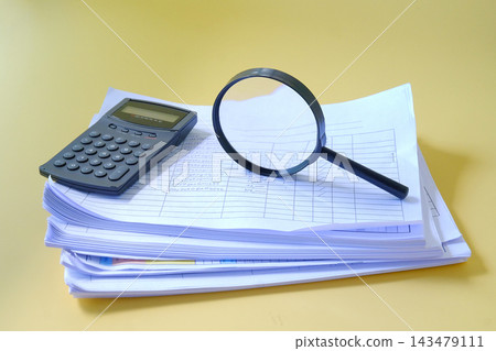 Magnifying glass and calculator on Stack of documents. Magnifying glass and calculator on Stack of documents. 143479111