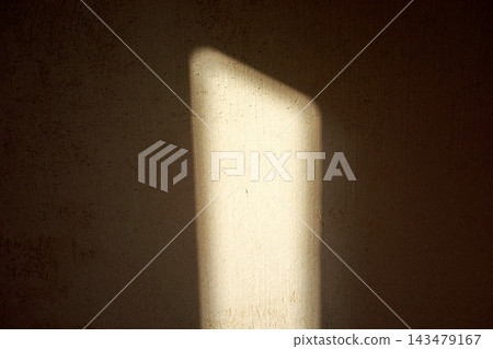 Close-up vertical illuminated panel on textured concrete wall with dramatic light and shadow, minimal abstract indoor background, warm tones in focus 143479167