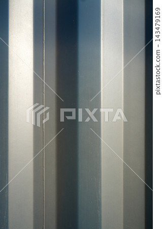 Blue gray vertical striped wall panel close-up with textured paint and soft shadow lines for architectural design backgrounds, indoor decor, and print layouts, minimal abstract surface detail 143479169