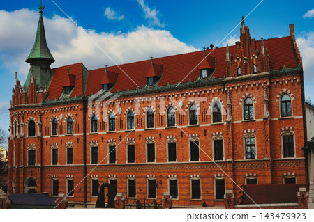 Grand historic red brick building with Gothic Revival architecture and a distinct green copper. 143479923
