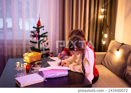 A child and adult write together at a table, surrounded by warm Christmas lights and a small decorated tree. A child and adult write together at a table, surrounded by warm Christmas lights and a small decorated tree. 143480072