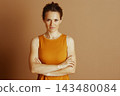 Confident Woman in Rust Top with Crossed Arms 143480084