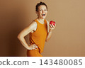 Smiling Woman Emphasizing Health with Apple 143480085