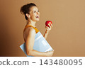 Joyful Woman Balancing Health with Apple and Scale 143480095