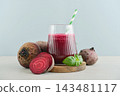 Beetroot juice in a glass with a striped paper straw, served with raw beetroot and fresh basil 143481117
