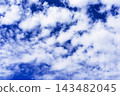 White clouds drifting across deep blue sky. Cloudscape and open sky background. Weather and atmosphere concept. Natural texture for design and copy space. 143482045