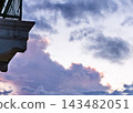 Cloud-filled evening sky beside a building balcony. Pink sunset colors over dramatic clouds. Atmospheric weather and changing skies. Urban architecture with open copy space. 143482051