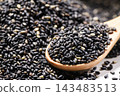Ingredient styling featuring black sesame seeds and scattered grains on a wooden spoon. 143483513