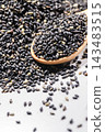 A photo of fragrant black sesame seeds served on a wooden spoon. 143483515