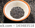 A photo of black sesame seeds served in a white bowl. 143483518